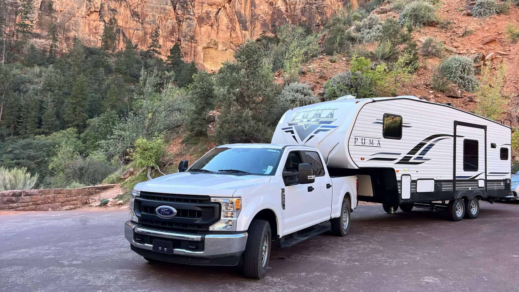 Flexible camping camper mit ford pick-up in einer malerischen naturumgebung, rot-orange felsen und dichte grüne bäume, ideal für outdoor-urlaub in den usa, all of usa reisefotografie.