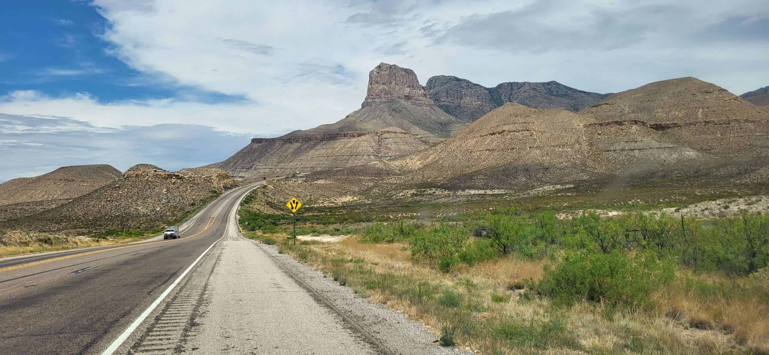 Fahrspur auf einer asphaltierter Straße in einer Wüstenregion mit Bergen im Hintergrund in den USA.