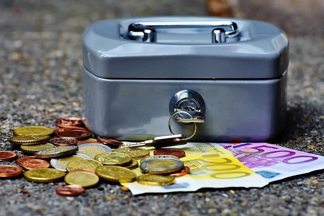 cashbox-1642989_640 Eine Geldkassette mit Schlüssel und davor Geldscheine und Münzen