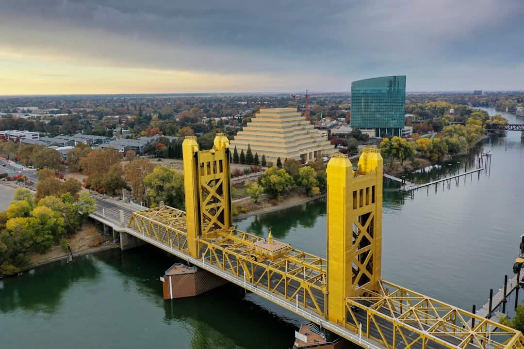 Photo by Leo_Visions a large yellow bridge over a river next to a tall building