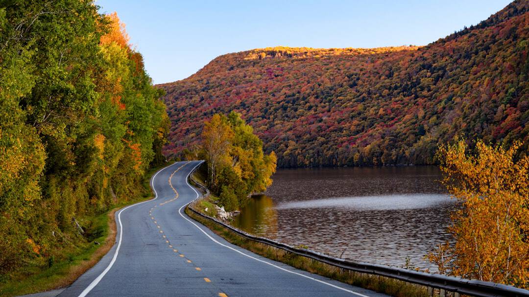 Photo by Abhi Verma a winding road with a lake in the background