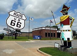 Elk,_oklahoma_03 Eine Statue und ein großes Route 66 Zeichen an einer Strasse