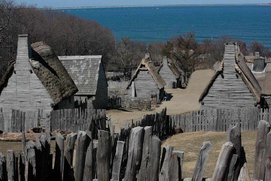 Photo by David Trinks An old village with a wooden fence and a body of water in the background