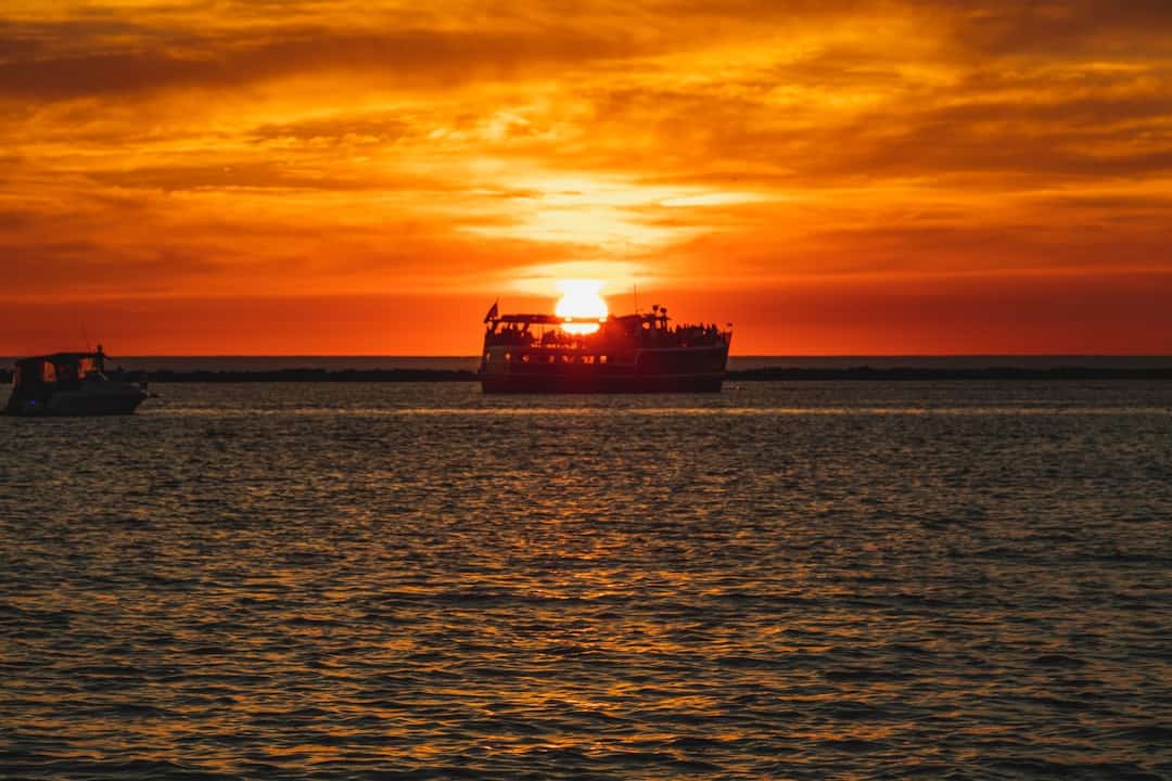 a boat in the water with the sun setting in the background