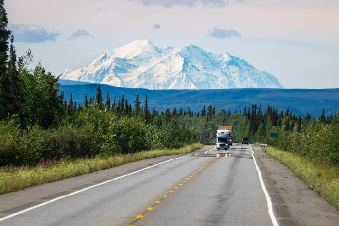 Photo by Joseph Corl A truck driving down a road with a mountain in the background