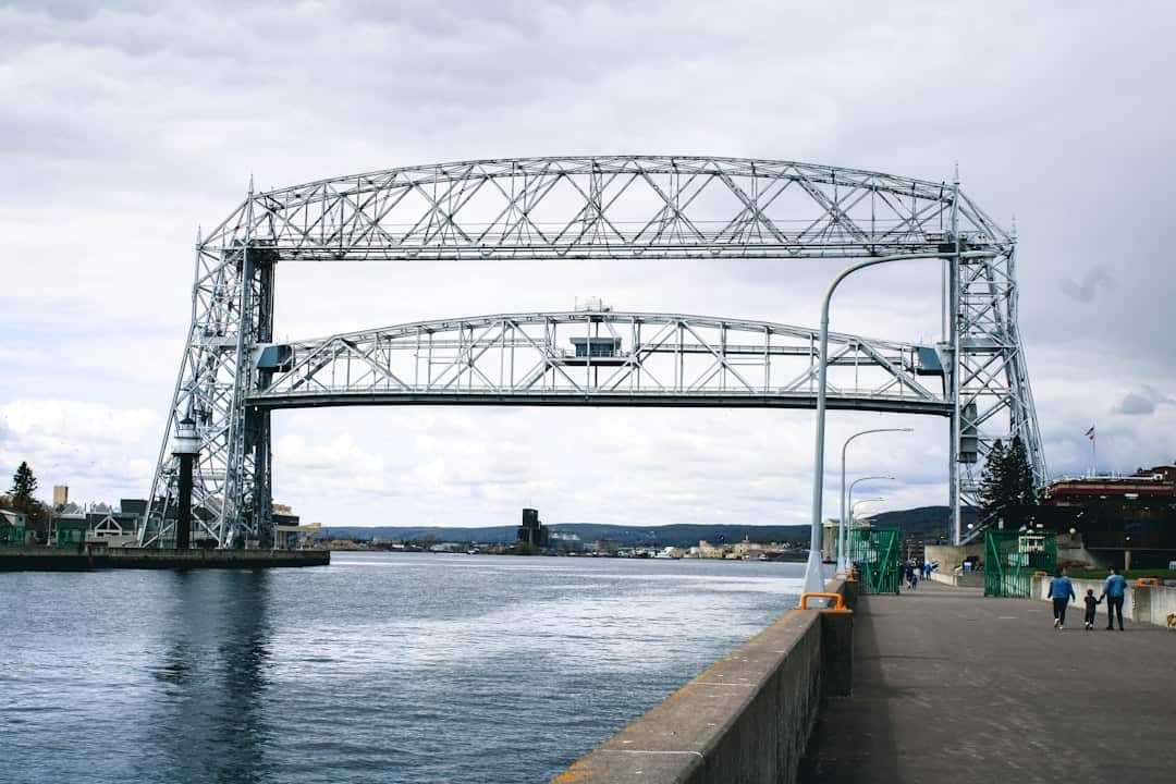 Photo by Cody Otto gray metal bridge over river under white sky during daytime