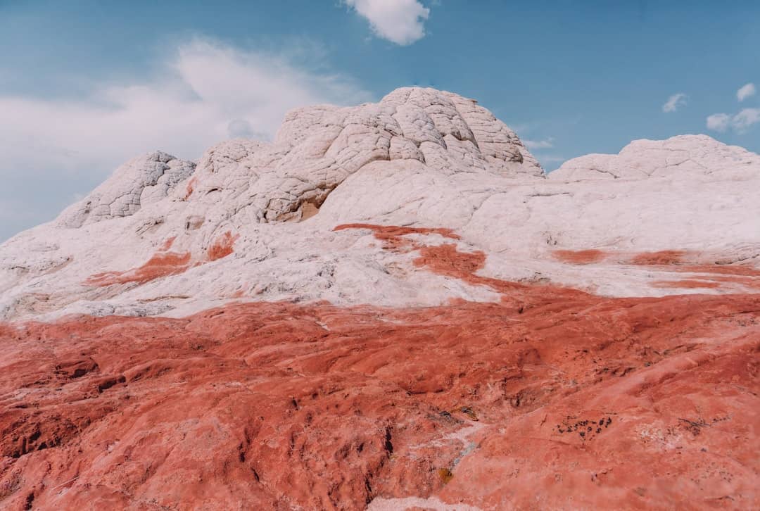 Photo by Yifu Wu a mountain covered in red dirt under a blue sky