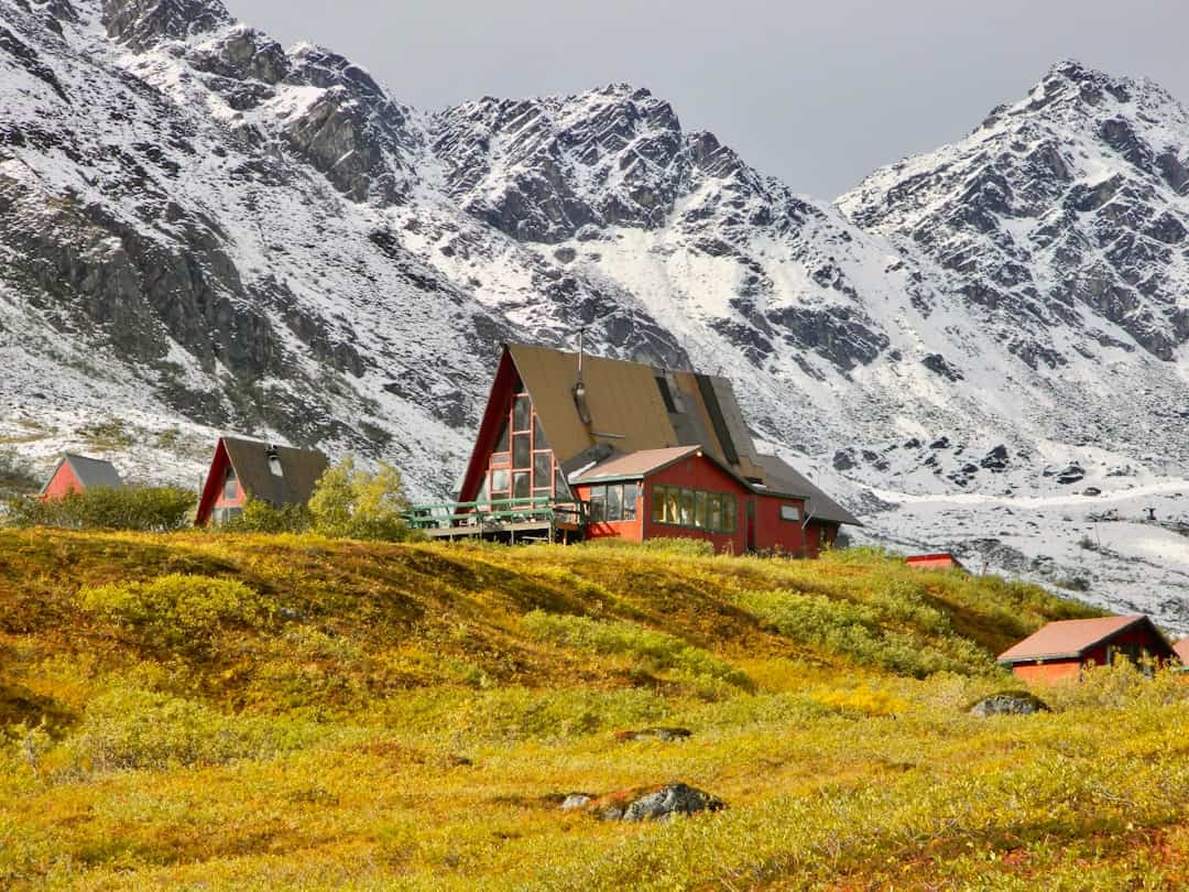 Photo by Daron Kuzina a red house sitting on top of a lush green hillside