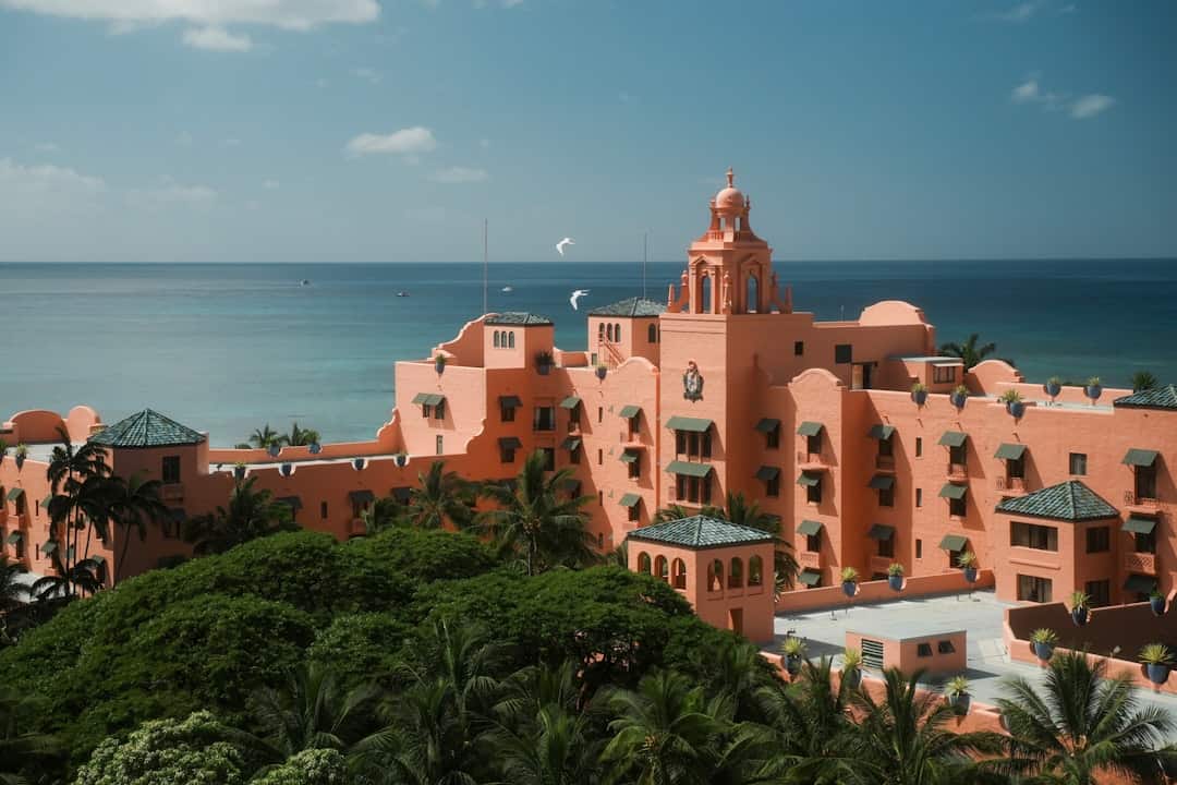 Pink historic hotel by the ocean with palm trees