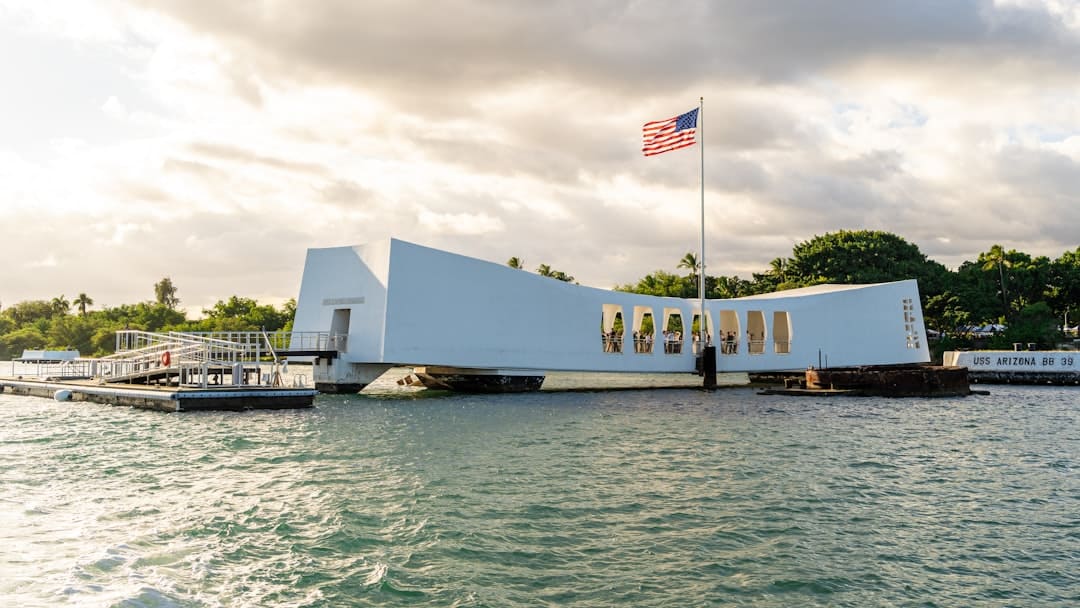 Photo by Winston Chen A large white building sitting on top of a body of water