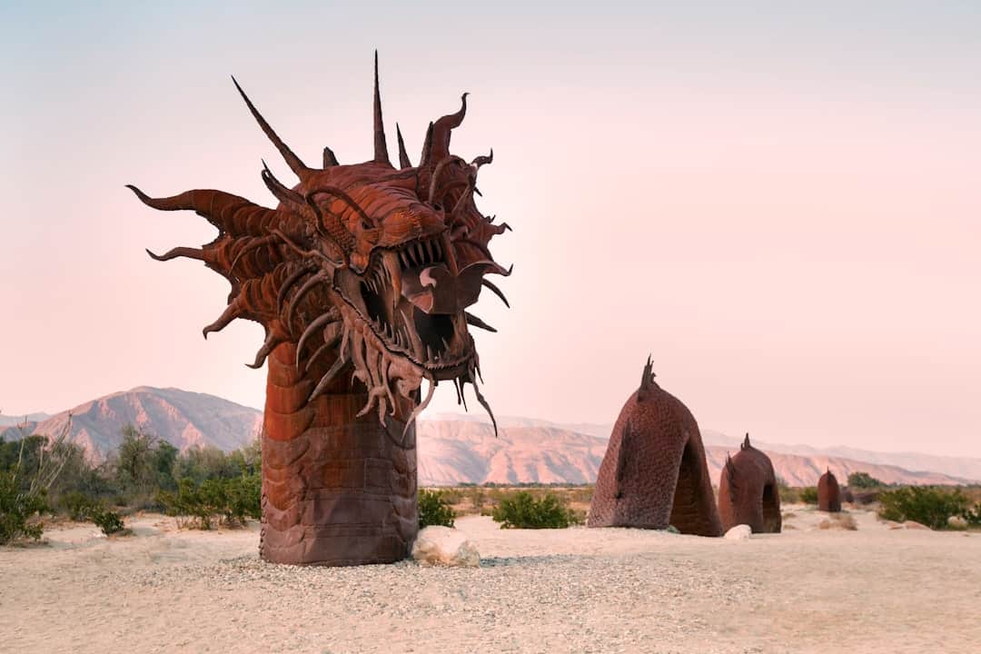 a sculpture of a dragon in the middle of a desert