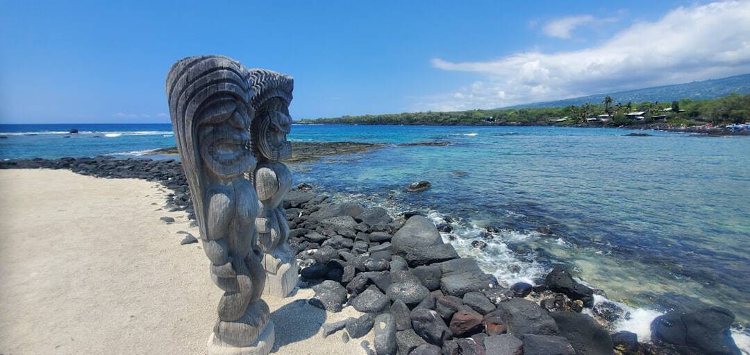 Photo by Stephen Wiggins a statue of an angel on a beach next to the ocean