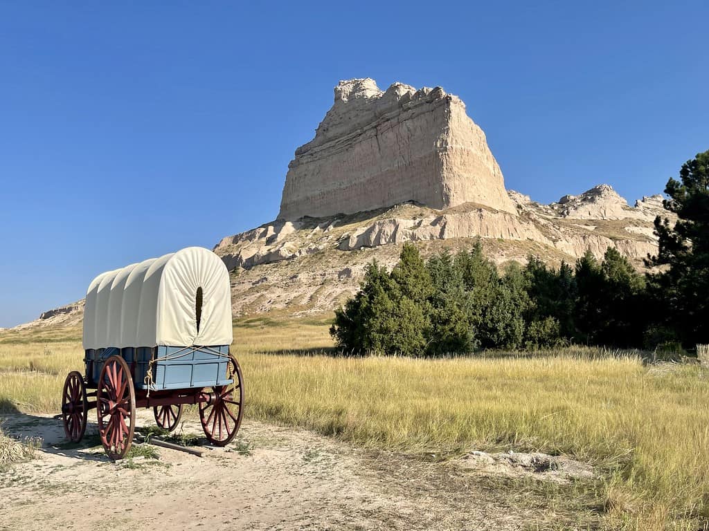 Historischer Planwagen vor den Felsen des Scotts Bluff National Monument in Nebraska